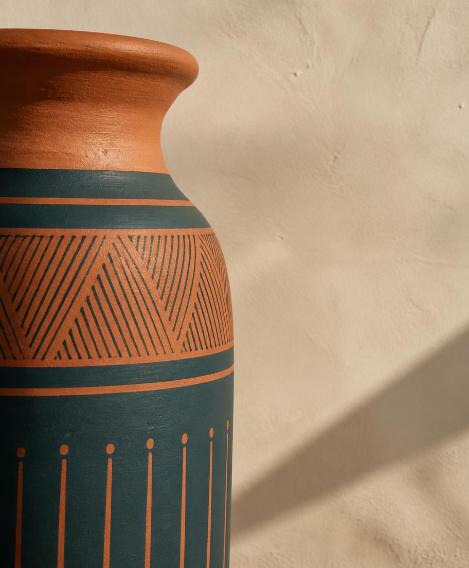 Terracotta and deep teal patterned vessel against a cream wall