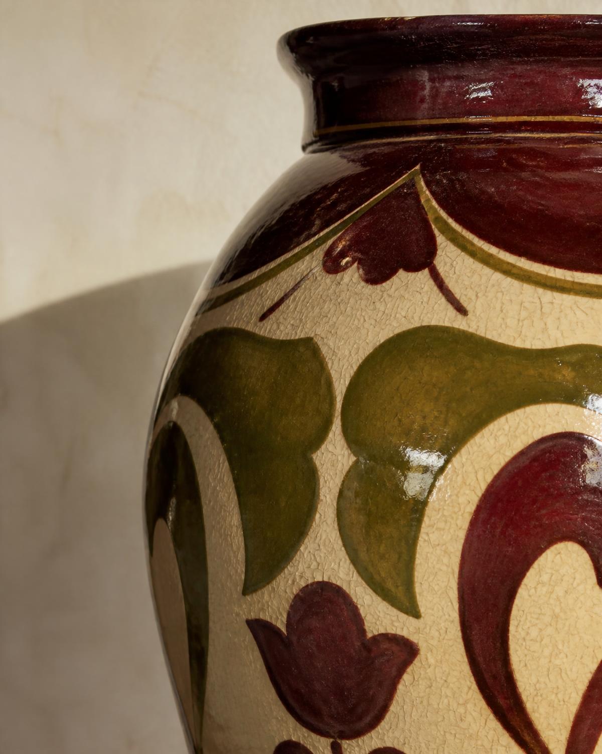 Tight crop of a burgundy and olive hand-painted decorative vessel